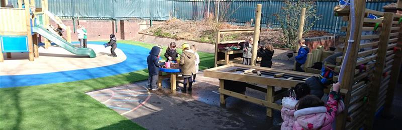 Outdoor playground with mud kitchen, tuff spot table and climbing frame